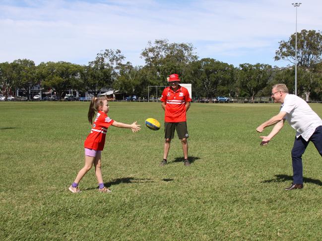 OVAL UPGRADE: Lismore Swans Junior AFL player Katrina McQuilty shows Ben Franklin how to hand ball as her father Nick looks on. Franklin was there to announce a $115,000 fencing upgrade for Mortimer Oval.