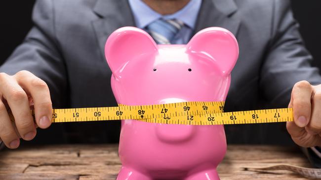 Midsection of businessman squeezing piggy bank with tape measure on wooden table, loan application generic