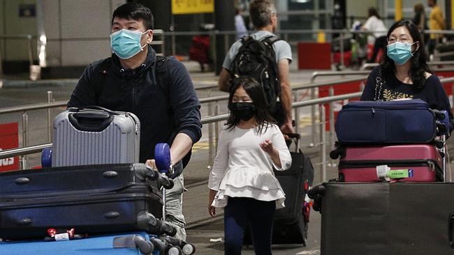 Travellers arrive at Melbourne Airport wearing face masks. Picture: Ian Currie