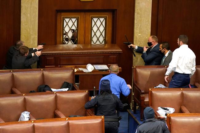 WASHINGTON, DC: U.S. Capitol police officers point their guns at a door that was vandalised in the House Chamber during a joint session of Congress. Picture: Drew Angerer / GETTY IMAGES NORTH AMERICA / AFP