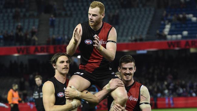 Adam Cooney is chaired off by Joe Daniher and Michael Hartley.