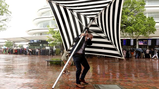 A punter shelters from the rain at Flemington Racecourse in Melbourne on Tuesday. Picture: Getty Images