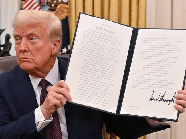 US President Donald Trump holds up an executive order he just signed to strenghten American leadership in digital financial technology, in the Oval Office of the White House in Washington, DC, on January 23, 2025. (Photo by ROBERTO SCHMIDT / AFP)