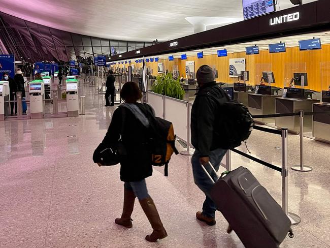 Travelers walk past a United Airlines counter at Washington's Dulles International Airport in Dulles, Virginia, on March 2, 2021 (Photo by Daniel SLIM / AFP)