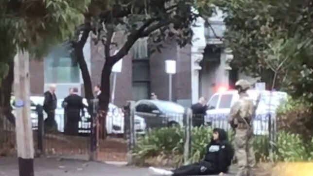 Video stills from supplied footage of counter-terrorism police outside a church in North Melbourne detaining a man on the ground.