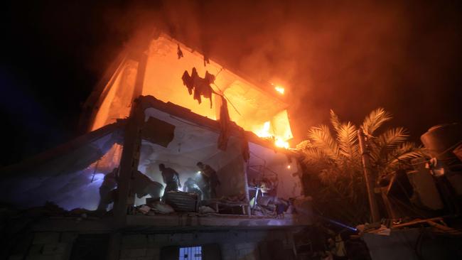 People use the lights on their telephones to search for victims amid the rubble of a smouldering building. Picture: Mahmud HAMS / AFP