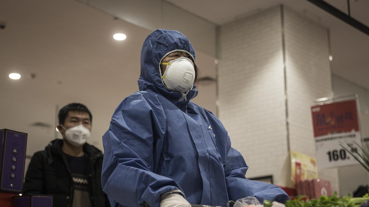 Residents wear protective clothes and mask as they line up to pay at a supermarket in Wuhan, China. Picture: Getty Images