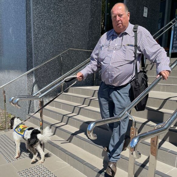 Peter George Reurich leaves Taree Court with support dog Boofhead on December 5.
