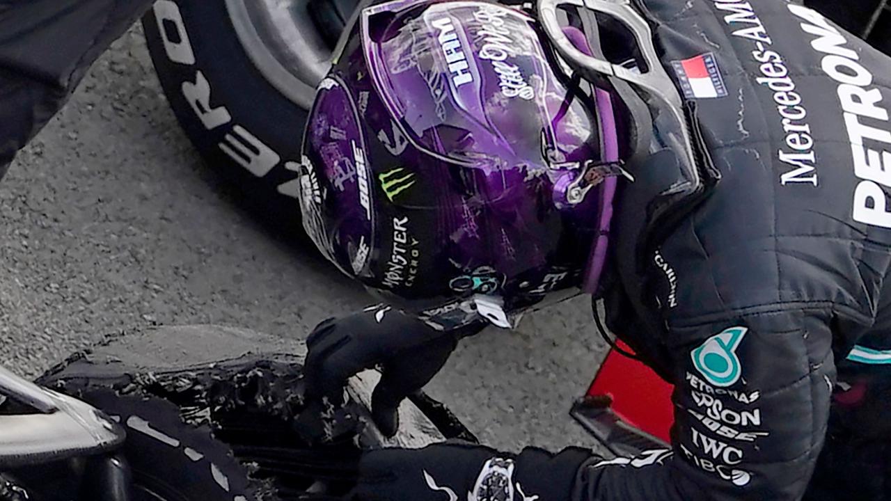 Mercedes' British driver Lewis Hamilton inspects his punctured tyre after he won the Formula One British Grand Prix.