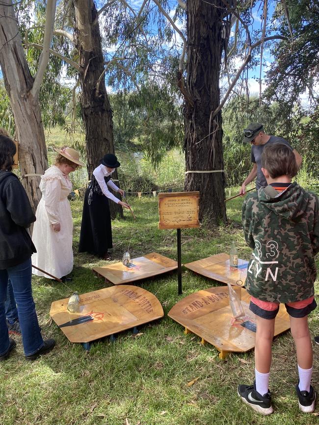 Adults and children playing an old-fashioned carnival game called Stand-A-Bottle. Picture: Niki Iliagoueva