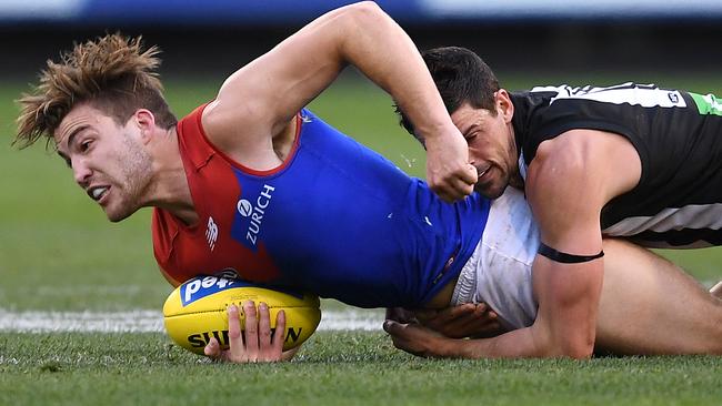 Melbourne co-captain Jack Viney is tackled by Scott Pendlebury.