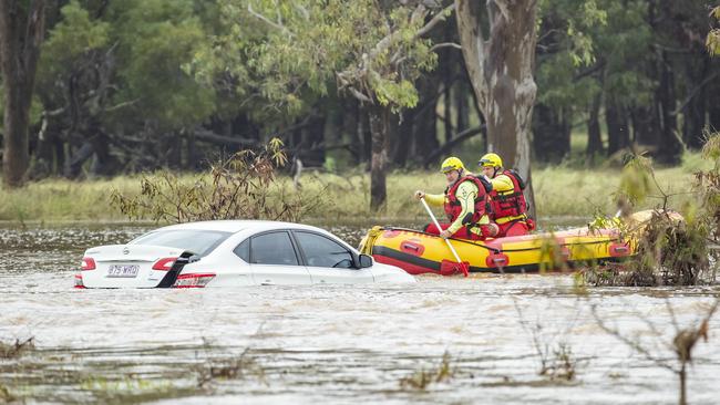 Queensland Fire and Emergency Services Swift Water Rescue check on a car in floodwaters last week. Picture: Richard Walker