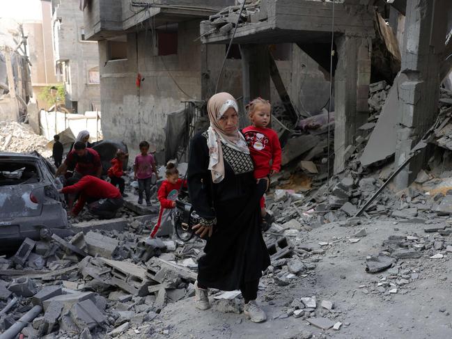 A Palestinian woman carries a toddler as she walks amid the destruction following Israeli strikes in Jabalia's Saftawi neighbourhood in the northern Gaza Strip on May 22. Picture: Bashar Taleb/AFP
