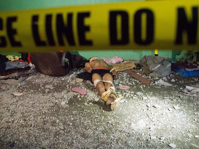 An alleged drug dealer, executed with hands bound and his head wrapped in tape, lies on a road behind police tape in Manila. Picture: Getty Images