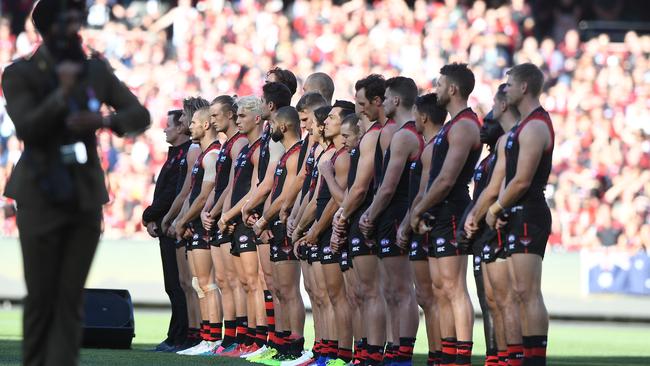 Essendon players stand during the Anzac ceremony in 2019.