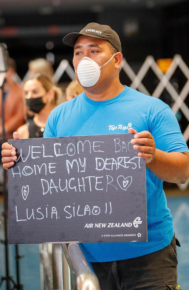 A man waiting at the arrivals hall holds out signage to welcome home his daughter on the first day of New Zealanders returning from Australia after the border reopened for travellers. Picture: AFP