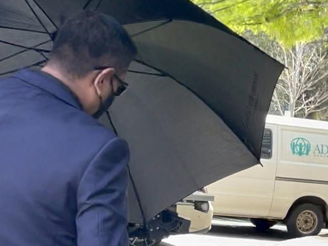 Shelvin Singh hid behind an umbrella as he left Hornsby Local Court.