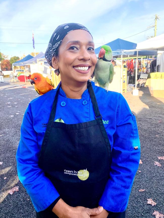 Dee Ibrahim-Milligan at her stall at the Bowral Market, where a customer's friendly parrots rest on her shoulders.