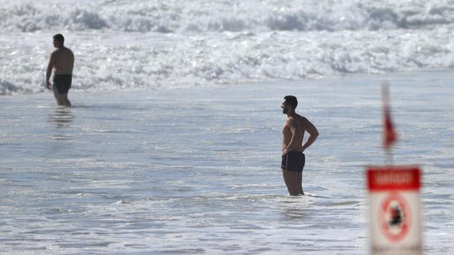 People in the water at Kurrawa Beach despite ‘no swimming’ signs. Photo: Scott Powick.