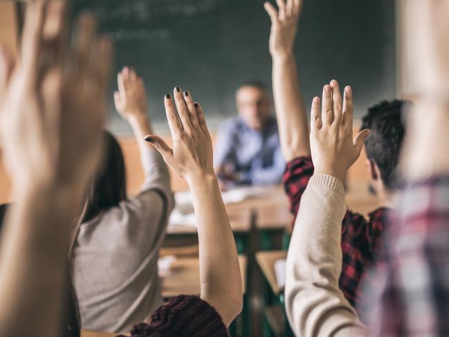 Rear view of group of students raising hands to answer teacher's question in the classroom. Focus is on hands in the middle.Picture: iStock