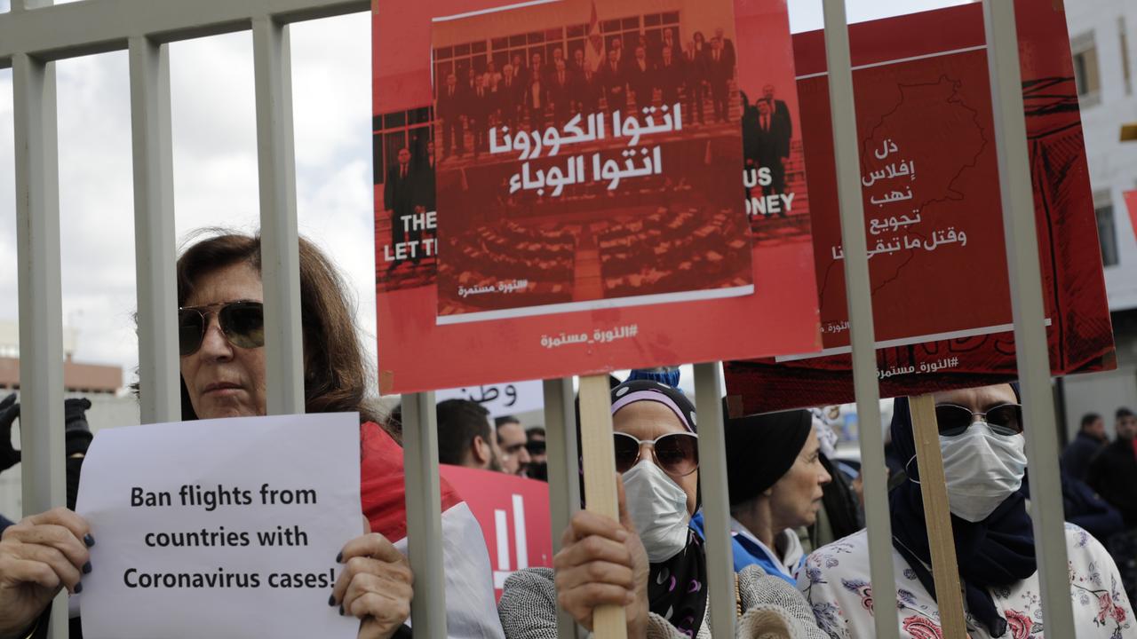 Anti-government protesters hold up banners in Arabic that read, ‘You are the coronavirus, you are the epidemic, and Humiliation, bankruptcy, looting, starving and killing the rest of us’ during ongoing protests against the Lebanese government in front of the Lebanese Ministry of Health, in Beirut, Lebanon. Picture: AP/Hassan Ammar.