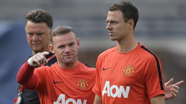 Manchester United's Wayne Rooney, left, talks with Jonny Evans as manager Louis van Gaal, left, watches during training for the their 2014 Guinness International Champions Cup soccer match against Real Madrid at Michigan Stadium in Ann Arbor, Mich., Friday, Aug. 1, 2014. (AP Photo/Paul Sancya)