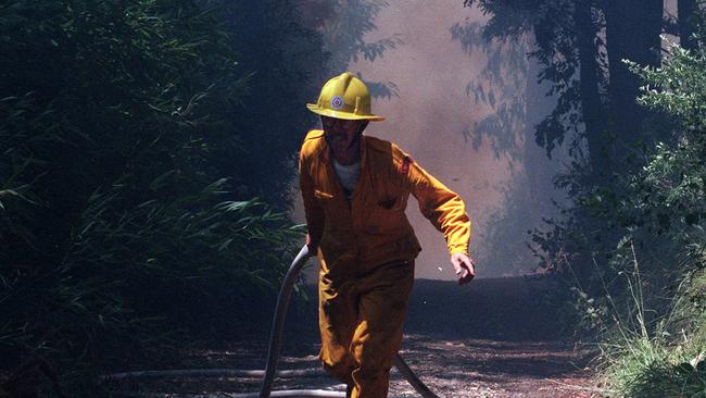 A firefighter races to a house on fire in Inverness Rd in the 1997 bushfire.