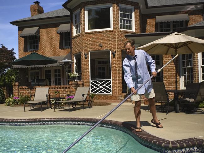 Man cleaning a pool.Real estate, house with a pool