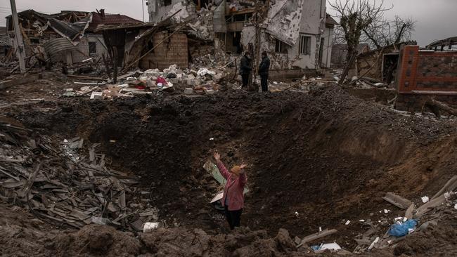 A woman waves as she stands in a crater following Russian missile attacks on January 26 in Hlevakha, outside Kyiv.