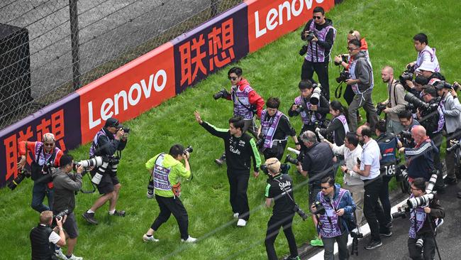 Chinese driver Zhou Guanyu surrounded by press and waving to fans at his home Grand Prix. (Photo by GREG BAKER / AFP)