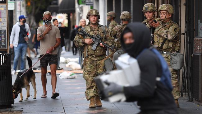 A looter carrying boxes of shoes runs past National Guard soldiers in Hollywood, California after a demonstration over the death of George Floyd. Picture: AFP