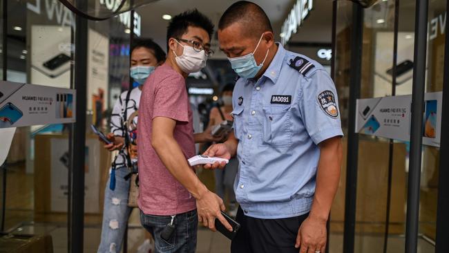 A guard checks the temperature of a customer as he enters a shop in Wuhan on Tuesday. Picture: AFP