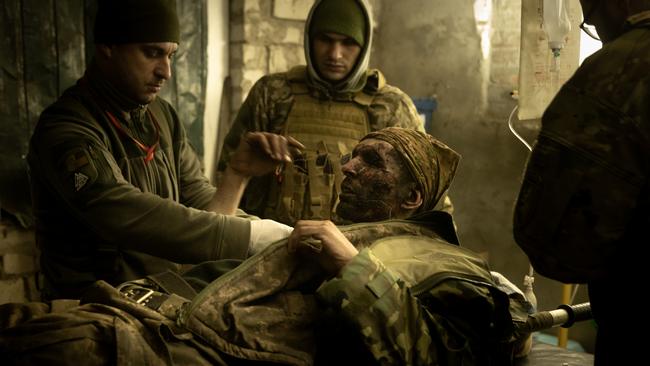 Military medics work on a member of the Ukrainian military suffering from head and leg injuries caused by a mine outside Bakhmut, Ukraine.