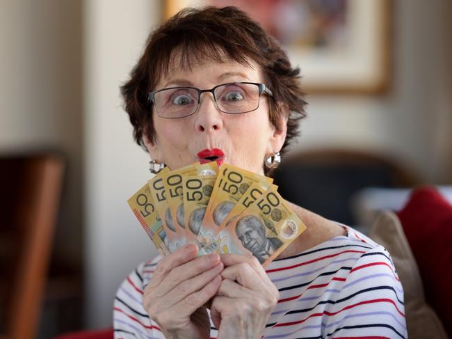 Woman with a surprised expression holding a fan of A$50  notes. Australian money generic banking