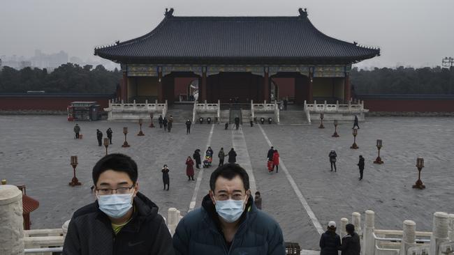 Chinese visitors wear protective masks as they tour the grounds of the Temple of Heaven, which remained open during the Chinese New Year and Spring Festival holiday in Beijing.