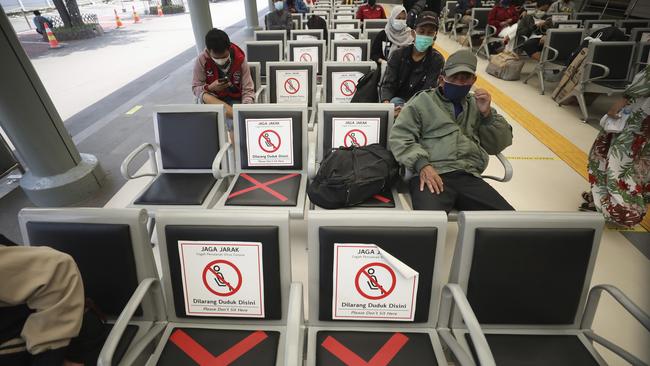 Men sit spaced apart as a social distancing effort to help curb the spread of the coronavirus in a train station waiting area in Jakarta. Picture: AP