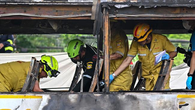 Rescue workers inspect the burnt bus. Picture: AFP