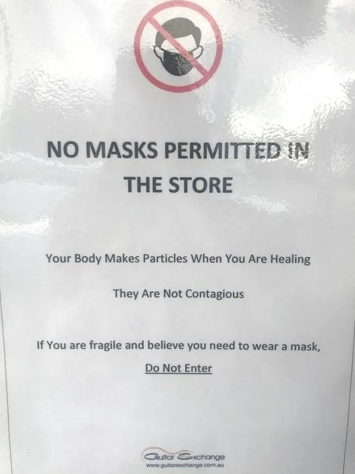 A "no masks permitted" sign displayed on the front door of Guitar Exchange in Morayfield.