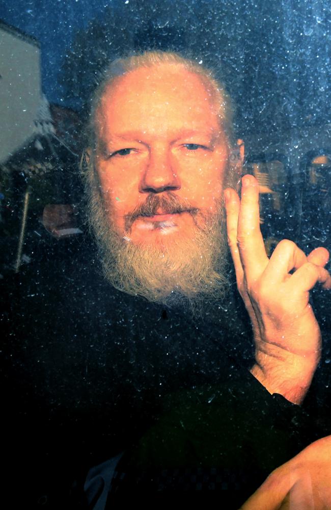 Julian Assange gestures to the media from a police vehicle on his arrival at Westminster Magistrates court. Picture: Getty