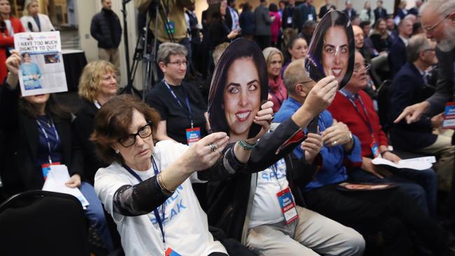 Liberal party members hold up Moira Deeming masks at a party conference. Picture: David Crosling