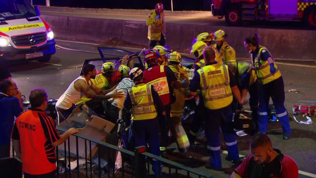 Up to a dozen emergency personnel with the help from bystanders work to get people out of the car. Picture: Active Media Images