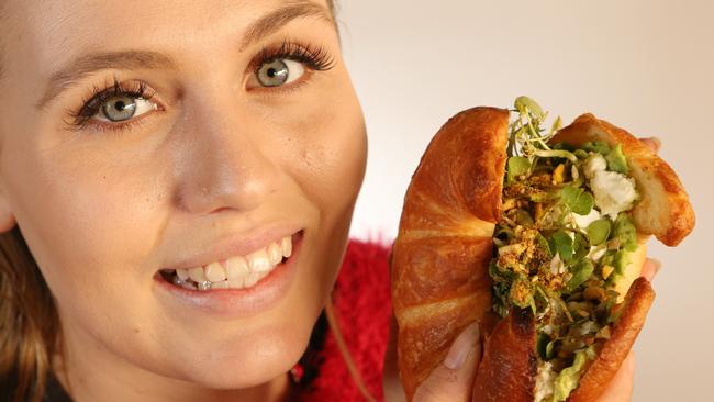 Local &amp; Co staff member Emma Stewart tucks into a Crushed Avo Croissant at the Main Beach Cafe. Picture Glenn Hampson