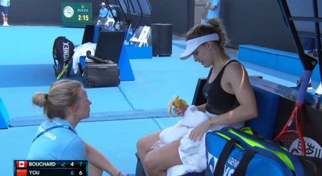 Eugenie Bouchard talks to a trainer as she battles the conditions.