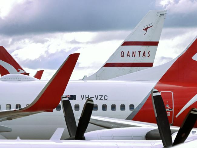 A photo taken on June 26, 2024 shows the vertical stabiliser of a Qantas Boeing 737-800 aircraft painted in heritage livery (background C) seen past other Qantas planes parked at a terminal at Melbourne's Tullamarine Airport. (Photo by William WEST / AFP)