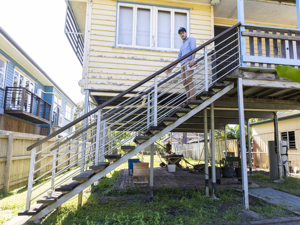 Courier-Mail reporter, Matty Holdsworth, on the stairs of a Tramore Street home, which was smashed by floods. The water level crept up to the third highest step. Picture : Matthew Poon.