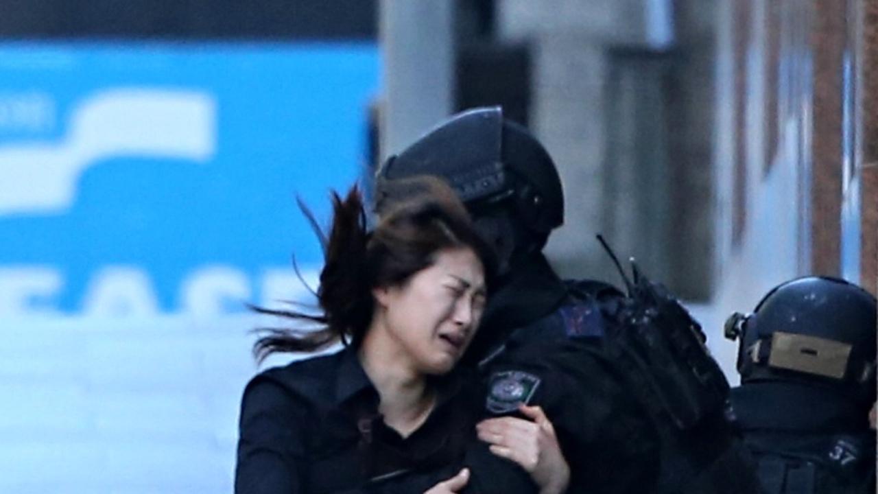 One of the escaped hostages is helped by police as she flees the Lindt Cafe siege in 2014.