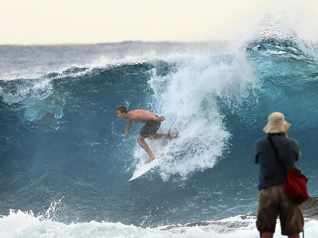 Photographers look on to a surfer at Snapper Rocks on the Gold Coast , Thursday February 21, 2019. Huge swells and high tides are set to pummelling south-east Queensland beaches over the coming days as Cyclone Oma tracks towards the Queensland coast. (AAP Image/Dave Hunt)