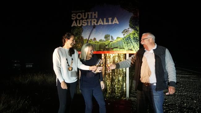 The Limestone Coast tourism industry, including Heidi Eldridge from Coonawarra Vignerons, Biddie Shearing from Limestone Coast Local Government Association and Grant Council Mayor Richard Sage, rolled out the red carpet to welcome Victorians back on Princess Highway as the South Australian border reopened to Victoria at midnight on Monday. Picture: Jessica Ball