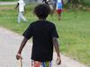 ### EMBARGOED UNTIL 13/4/2024 ###
A young aboriginal boy arms himself with a rock and a length of wood before walking towards other boys playing in the street in Aurukun, a small indigenous town on the Gulf of Carpentaria, 800 kilometers north northwest of Cairns on Cape York in Far North Queensland. Picture: Brendan Radke