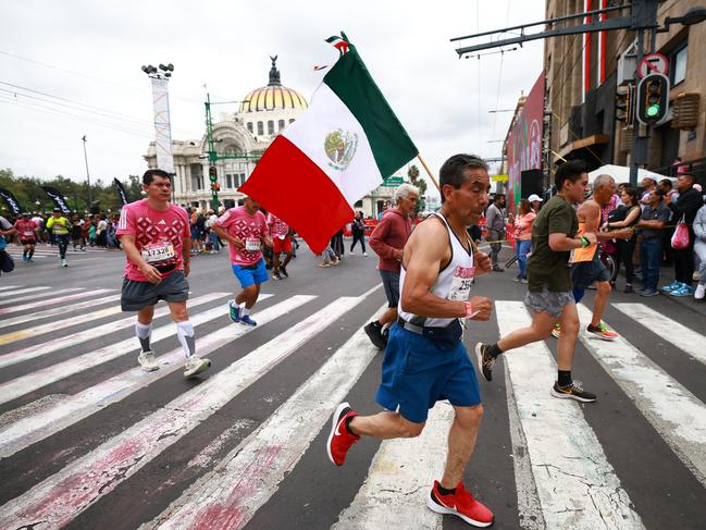 MEXICO CITY, MEXICO - AUGUST 27: Runner competes with a Mexico flag during the 2023 Mexico City Marathon on August 27, 2023 in Mexico City, Mexico. (Photo by Hector Vivas/Getty Images)